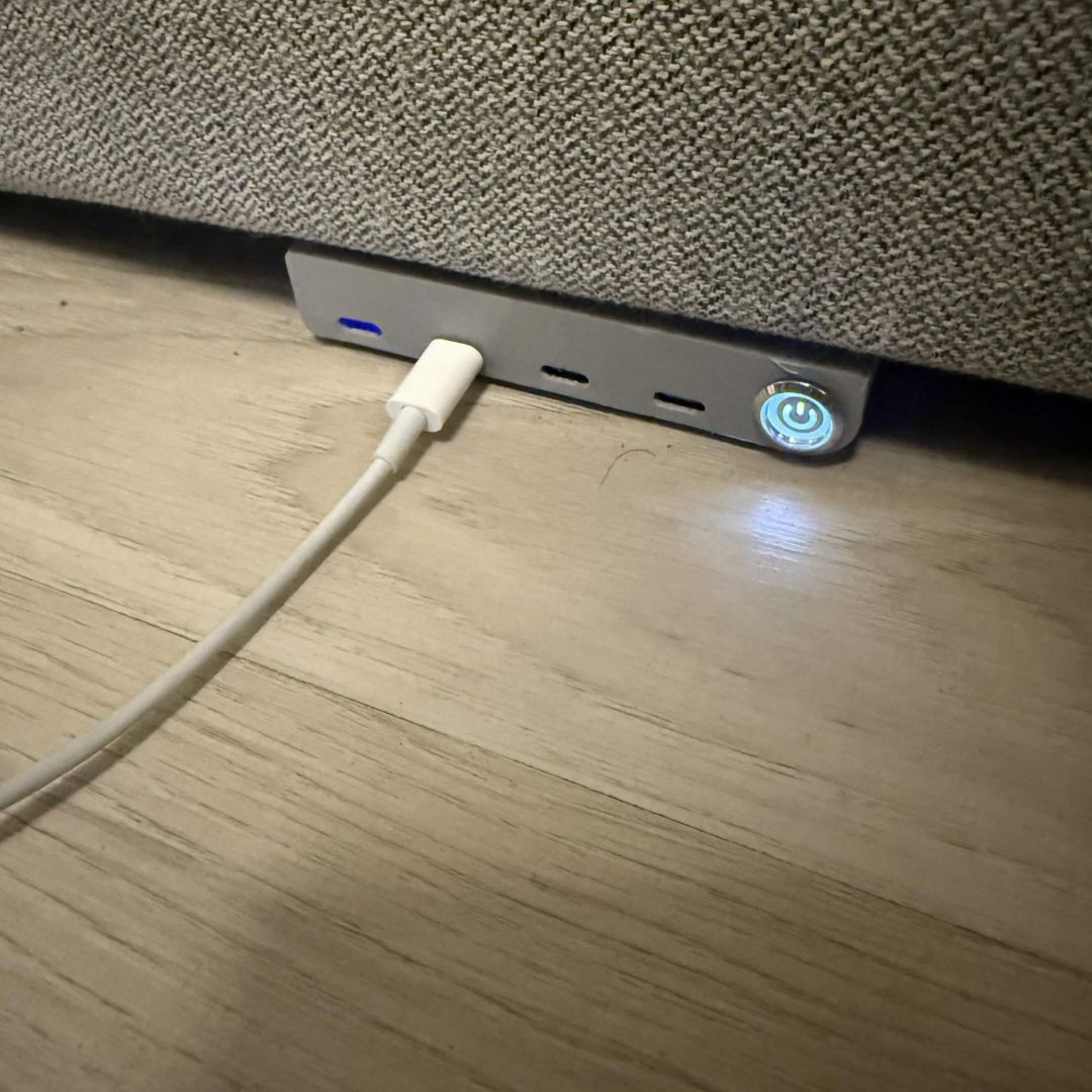 The same dock with its power button lit blue and a port indicator glowing, a cable plugged in.
